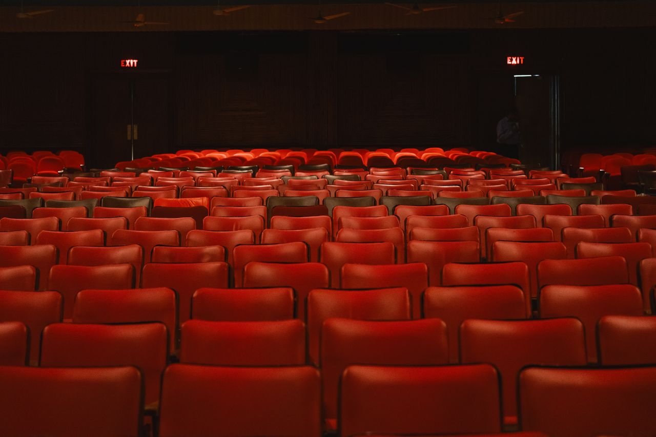 Rows of empty red seats inside a classic movie theater with a vintage ambiance.